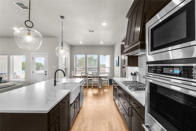 kitchen with visible vents, light wood-style flooring, a sink, appliances with stainless steel finishes, and backsplash