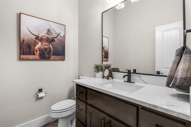 bathroom featuring vanity, toilet, and baseboards