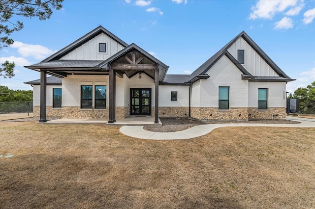 modern farmhouse style home featuring board and batten siding, a front lawn, and fence