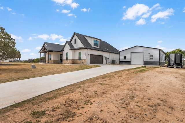 modern farmhouse style home featuring an outbuilding, a front lawn, stone siding, board and batten siding, and concrete driveway