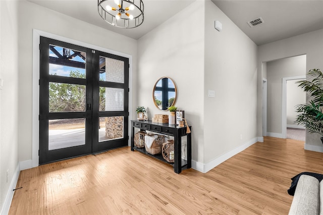 entrance foyer with a notable chandelier, wood finished floors, visible vents, and baseboards