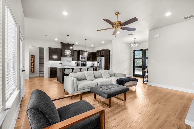 living room featuring visible vents, baseboards, recessed lighting, ceiling fan with notable chandelier, and light wood-type flooring