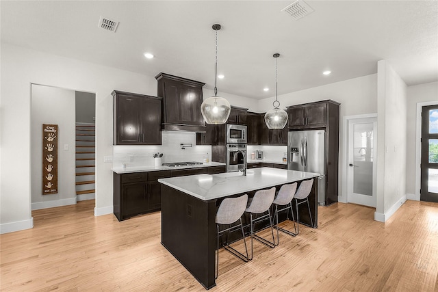 kitchen featuring light wood finished floors, visible vents, backsplash, and appliances with stainless steel finishes