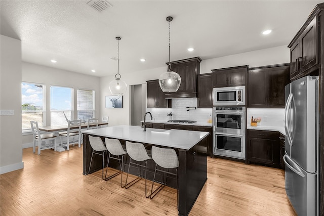 kitchen with visible vents, backsplash, stainless steel appliances, and light wood-type flooring