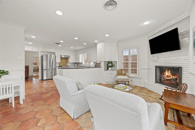 living area featuring visible vents, recessed lighting, a warm lit fireplace, and ornamental molding