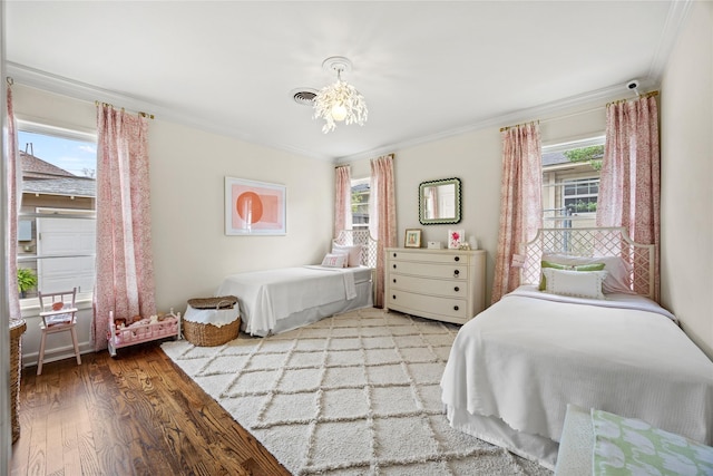 bedroom featuring visible vents, wood finished floors, and ornamental molding