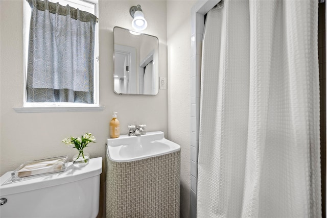 full bathroom featuring a shower with shower curtain, toilet, and a sink