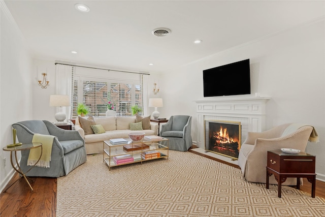 living area featuring visible vents, baseboards, wood finished floors, and a fireplace