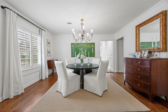 dining area featuring wood finished floors, baseboards, visible vents, ornamental molding, and a notable chandelier