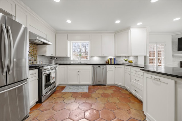 kitchen featuring stainless steel appliances, dark countertops, a healthy amount of sunlight, and range hood