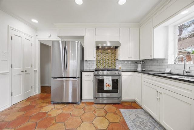 kitchen featuring a sink, dark countertops, appliances with stainless steel finishes, and wall chimney range hood