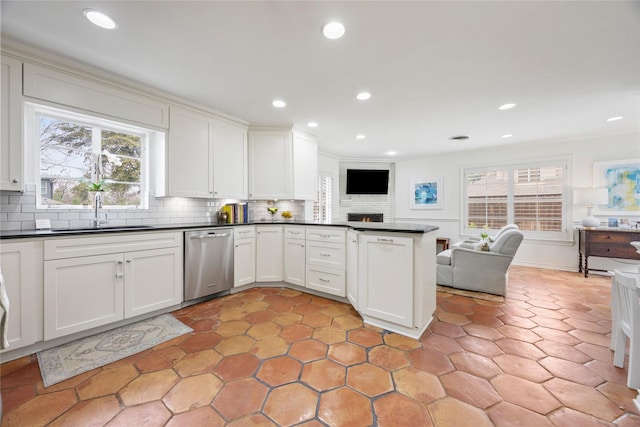 kitchen featuring stainless steel dishwasher, dark countertops, open floor plan, and a sink