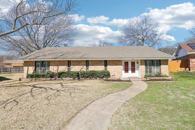 ranch-style home featuring brick siding, a shingled roof, a front yard, and fence