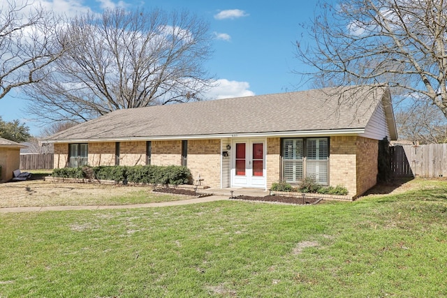 single story home featuring a front yard, fence, brick siding, and roof with shingles