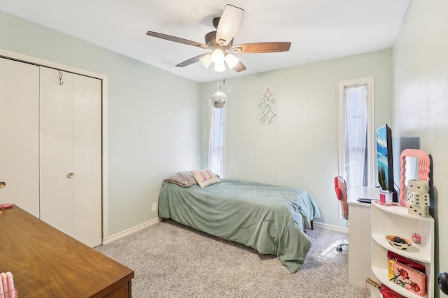 carpeted bedroom featuring a ceiling fan, a closet, and baseboards