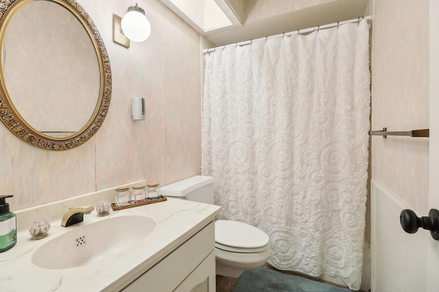 bathroom with toilet, a skylight, vanity, and a shower with curtain