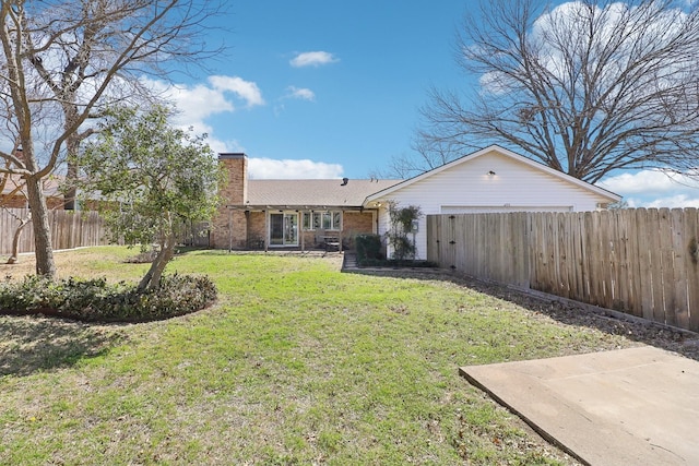 rear view of house featuring an attached garage, a fenced backyard, a chimney, a lawn, and brick siding