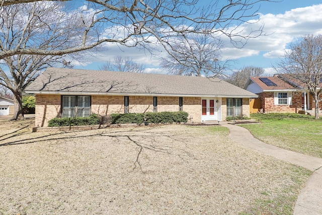 single story home with brick siding, roof with shingles, and a front yard