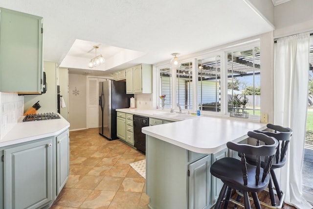 kitchen featuring a sink, a raised ceiling, backsplash, and appliances with stainless steel finishes