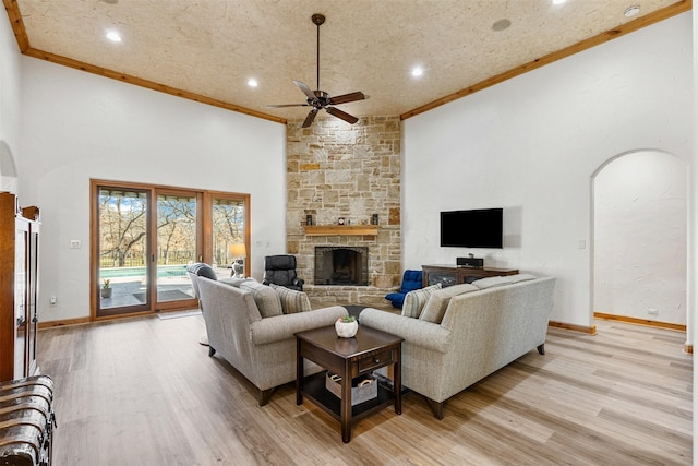 living area featuring crown molding, baseboards, a ceiling fan, and light wood-type flooring