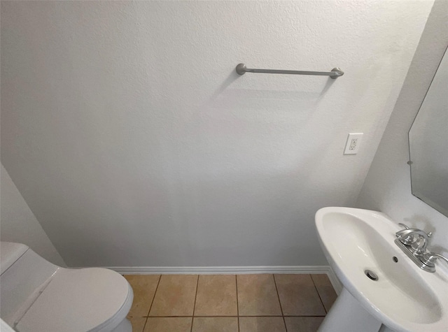 bathroom with tile patterned floors, baseboards, toilet, and a sink