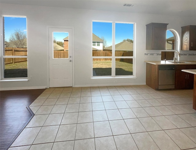 kitchen featuring visible vents, a sink, tasteful backsplash, stainless steel dishwasher, and light countertops