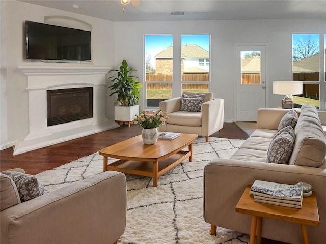 living room featuring a glass covered fireplace, wood finished floors, and visible vents