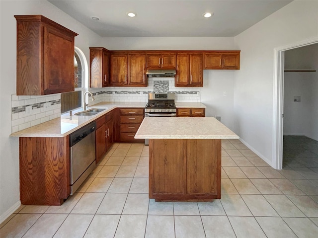 kitchen with a sink, under cabinet range hood, appliances with stainless steel finishes, light countertops, and light tile patterned floors