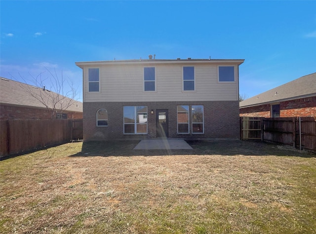 back of house with brick siding, a fenced backyard, a lawn, and a patio area