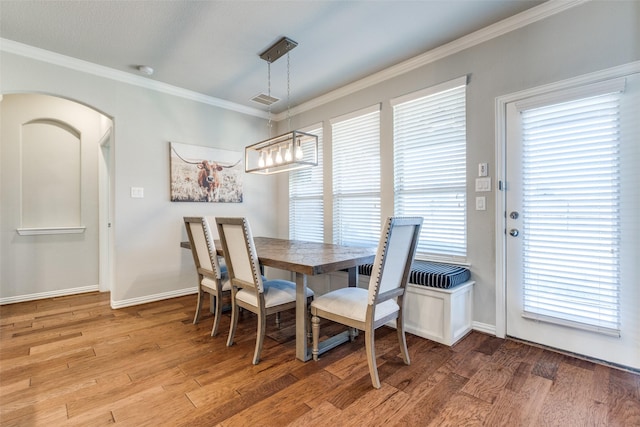 dining room featuring arched walkways, visible vents, light wood-type flooring, and crown molding