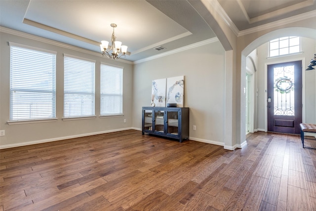 foyer entrance featuring a tray ceiling, wood finished floors, and arched walkways