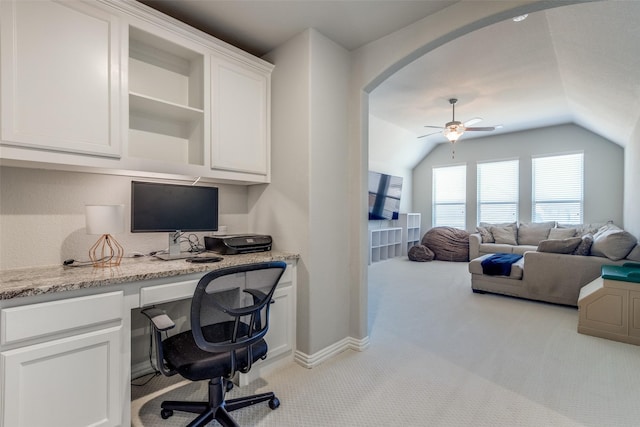 office area featuring built in desk, carpet flooring, baseboards, ceiling fan, and vaulted ceiling