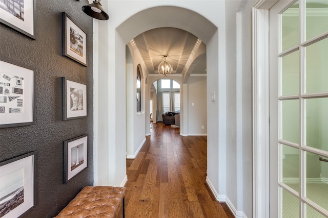 hallway with baseboards, arched walkways, ornamental molding, and hardwood / wood-style flooring