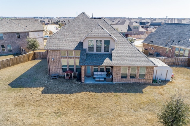 back of property featuring a lawn, brick siding, and roof with shingles