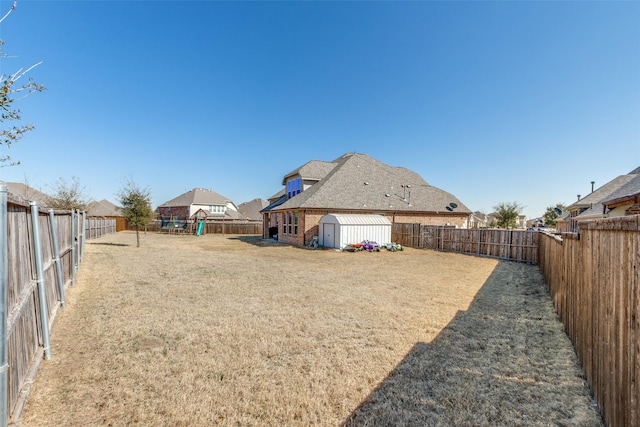 view of yard featuring a storage unit, a fenced backyard, and an outdoor structure