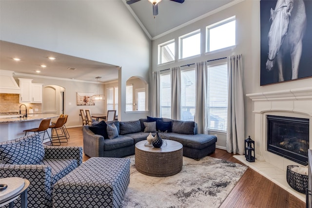 living room featuring wood finished floors, arched walkways, a high end fireplace, and ornamental molding