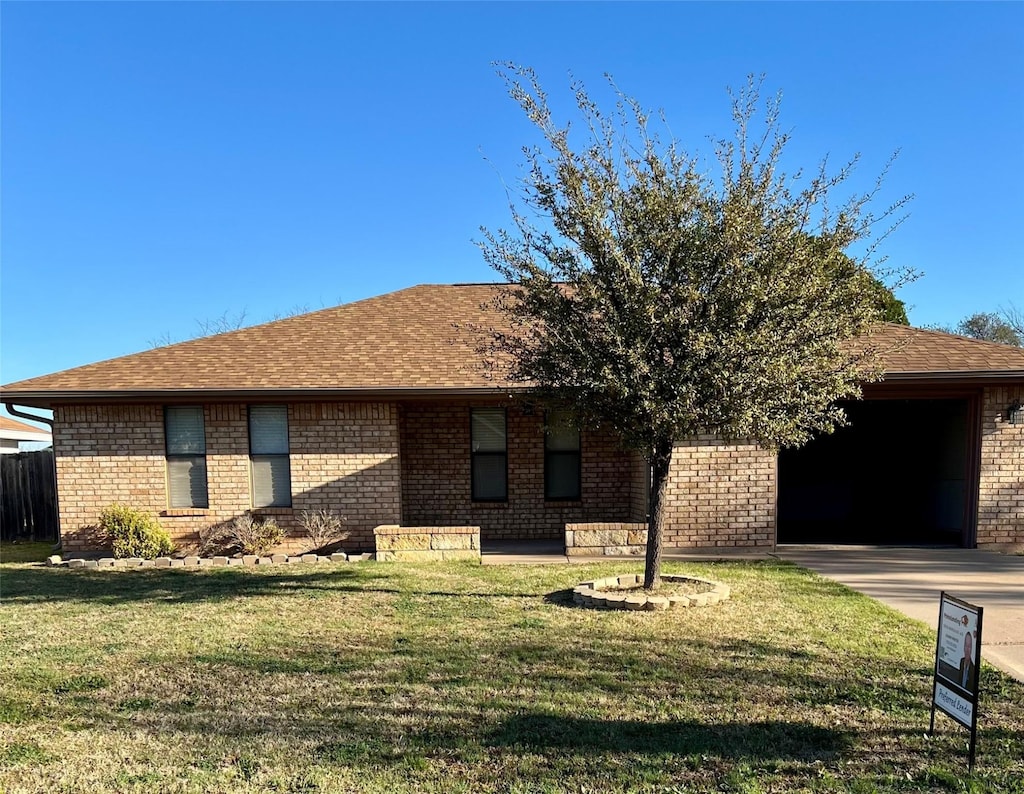 view of front of property featuring brick siding, driveway, a front yard, and a garage