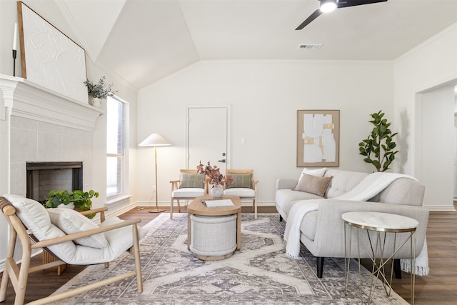 living room featuring wood finished floors, visible vents, lofted ceiling, ceiling fan, and a tiled fireplace