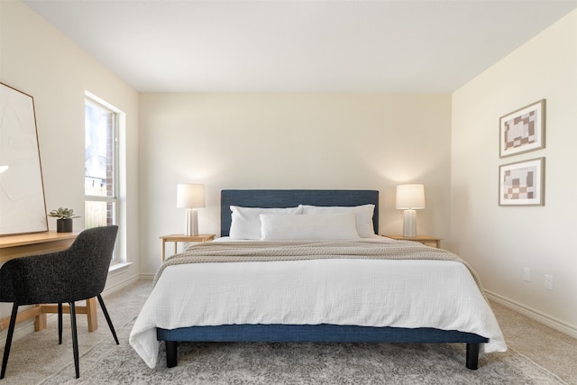 bedroom with light colored carpet and baseboards