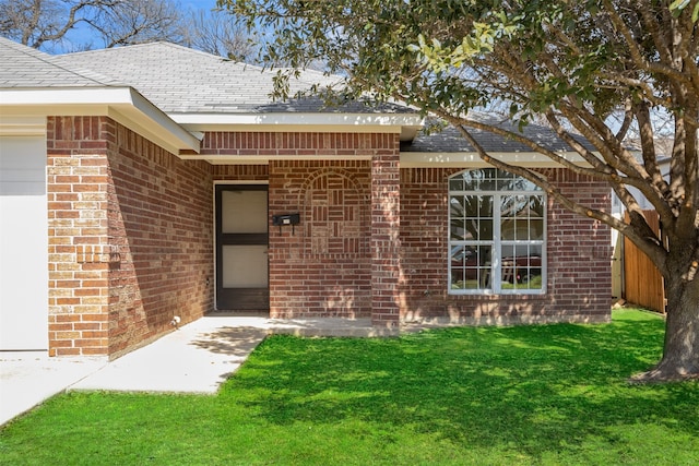 property entrance featuring a garage, a yard, and brick siding