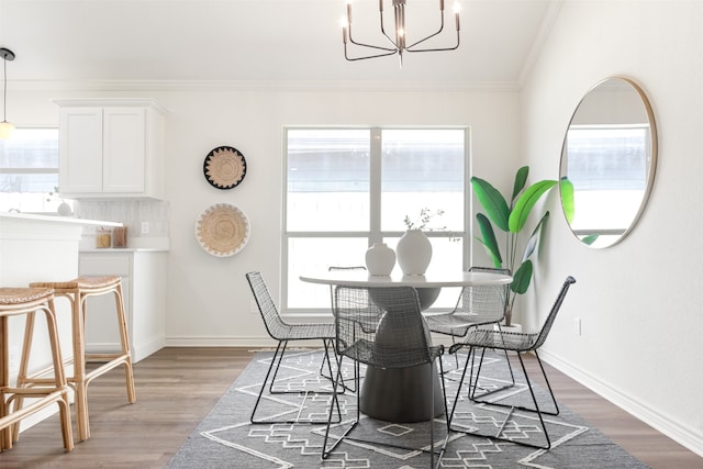 dining room with a chandelier, wood finished floors, baseboards, and ornamental molding