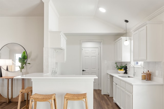 kitchen with a sink, white cabinetry, dark wood-type flooring, and vaulted ceiling