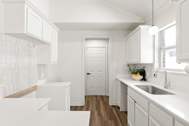 kitchen featuring ornamental molding, a sink, light countertops, white cabinetry, and tasteful backsplash