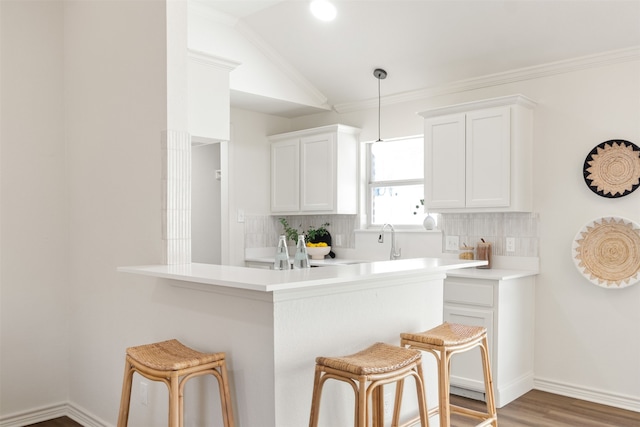 kitchen with light countertops, a kitchen breakfast bar, backsplash, and ornamental molding