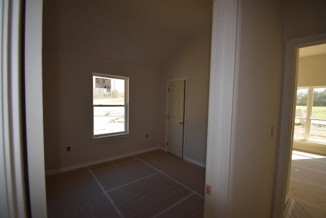 spare room with baseboards and vaulted ceiling