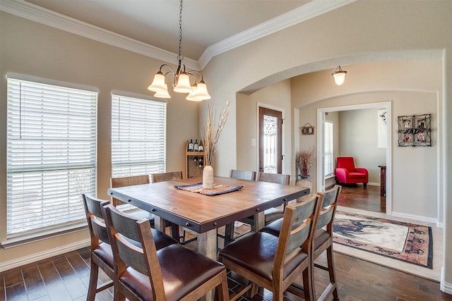 dining space with arched walkways, dark wood-type flooring, baseboards, and ornamental molding