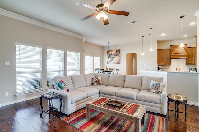 living area featuring visible vents, arched walkways, baseboards, and dark wood finished floors