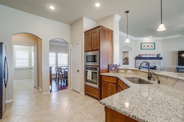 kitchen with light tile patterned flooring, appliances with stainless steel finishes, light stone countertops, and a sink