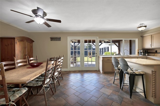 dining space with crown molding, stone finish floor, french doors, and ceiling fan