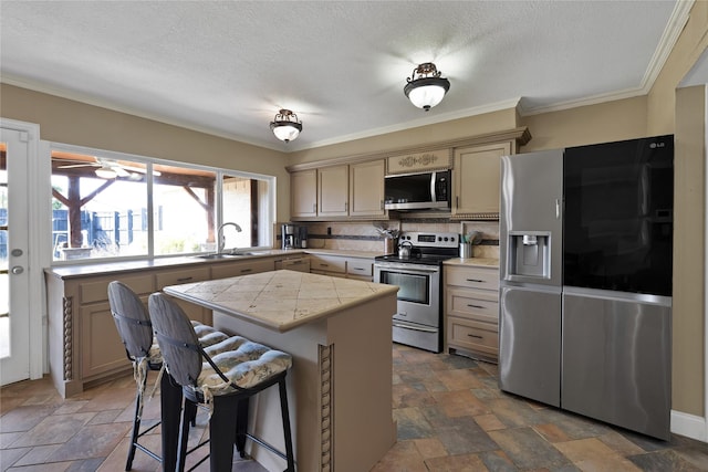 kitchen with stone tile floors, a sink, appliances with stainless steel finishes, tasteful backsplash, and a center island